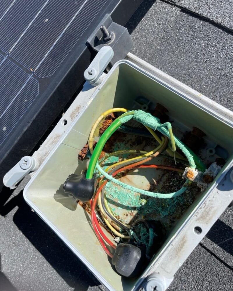 Heavy green copper corrosion on the conductors inside an opened rooftop junction box on a solar installation.